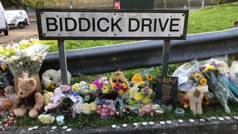 Flowers lay next to Biddick Drive sign