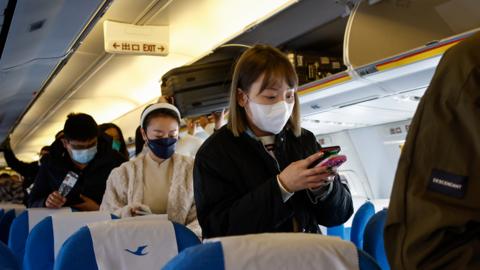 Passengers prepare to disembark upon arrival at the Beijing Daxing International Airport in Beijing, China, 26 December 2022