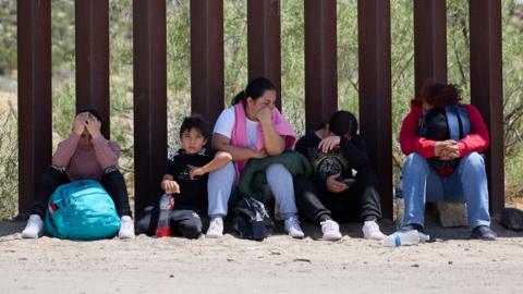 Migrants wait for US Border Patrol after crossing the US Mexico border in California