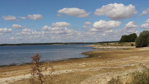 A large reservoir of water with long, dry banks around the edges.