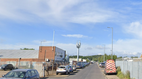 Blue House Point Road which is lined with industrial buildings and cars