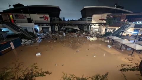 The shopping centre with debris floating in brown floodwater