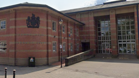 A large red brick building with a number of large windows and a sign stating Crown Court and County Court