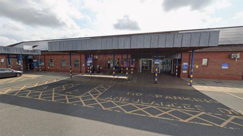 The main entrance to Bridlington Hospital. It has a grey canopy over the doors and an ambulance parking bay in front marked in yellow paint