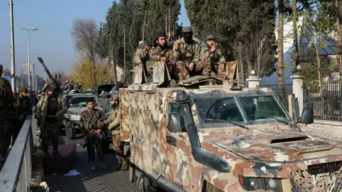 Rebel fighters sit on a vehicle, after rebels seized the capital and ousted President Bashar al-Assad, in Damascus, Syria, December 9,