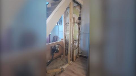 Mr Arnison's downstairs showing the wall underneath his stairs removed leaving a wooden support and exposed electrics