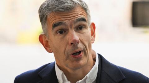 A close up of Matt Brittin on arrival at BBC HQ in London, wearing a white shirt and a dark suit jacket