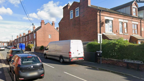 A residential street with houses and cars parked on the road. There is a street sign which reads 'Elizabeth Street'.
