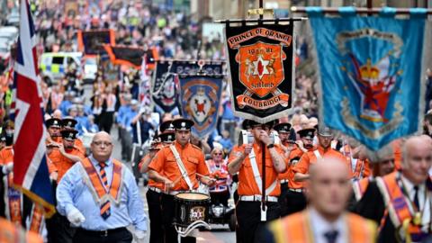 Members of the Orange Order and their supporters march through the city