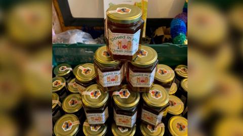 Jars of honey stacked up. The jars have Rooted in Hull labels, which carry an image of the Humber Bridge. 