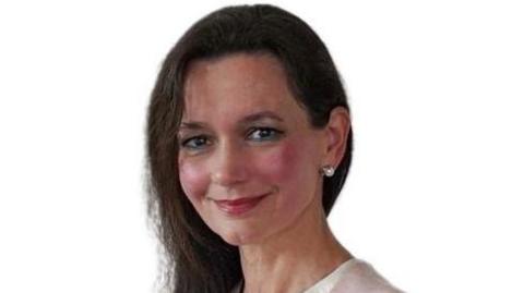 Picture of Maria Cristina Cherino Munoz she has long dark hair and is wearing a white shirt and pink jacket