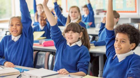 children at primary school with their hands up