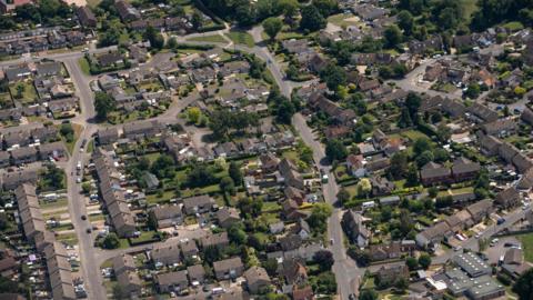 Aerial view flying over rows of neatly lined townhouses in Slough.