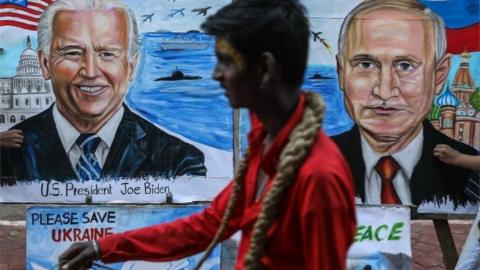 A man walks past students of the Gurukul School of Art painting portraits of US President Joe Biden and Russian President Vladimir Putin with a message wishing peace between Ukraine and Russia, in Mumbai, India, 21 February 2022.