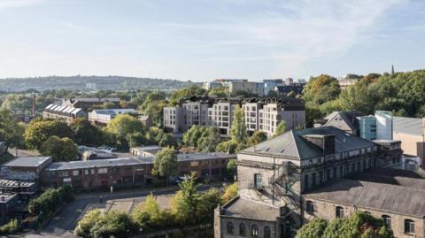An artists impression of what the flats would look like in the Ouseburn Valley. There are several large, grey buildings with large windows among the stone and brick buildings. 