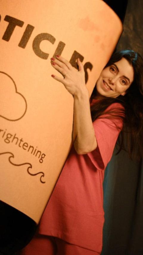 Presenter Josie Peters holding a large bottle labelled particles