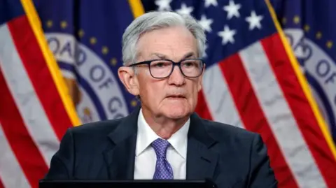 Federal Reserve Chair Jerome Powell stands in front of an American flag