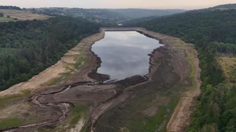Drone image of a reservoir in England with depleted water. The dried out banks of the reservoir can be seen