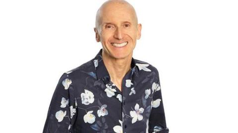 Promo picture of Bill wearing a flowery blue smart shirt.