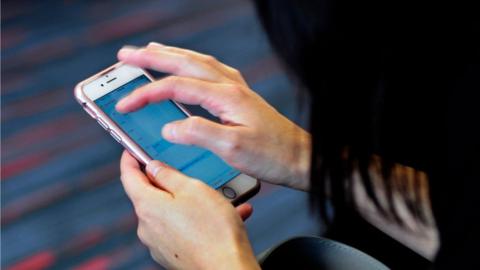 A woman uses her smartphone while waiting to board a plane at the Dallas/Fort Worth International Airport, on 21 September 2017