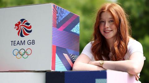Kirsty Muir stands next to Team GB promotional cube that features a Lion emblem, the words TEAM GB and the Olympic rings