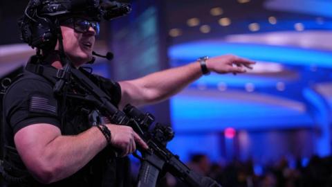 An armed Secret Service agent stands on stage following the shooting. He is dressed in black body armour and is heavily armed
