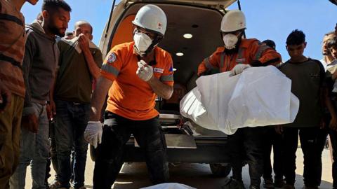 Civil defense teams carry the body of a Palestinian following an Israeli airstrike on residential areas in central Khan Yunis, southern Gaza, on May 23, 2025.