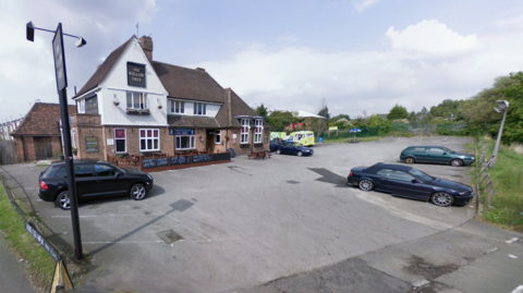 A general view of a pub with a car park.