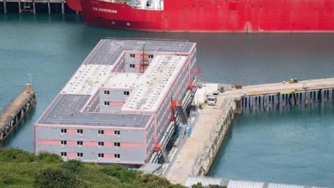 A red and grey barge on blue water. 