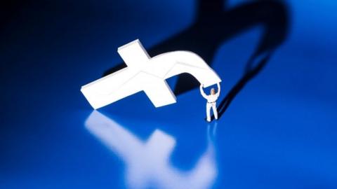 Tiny man carrying Facebook "F"