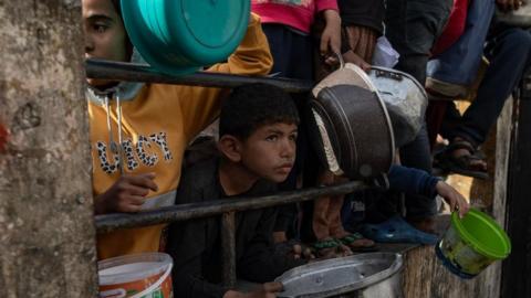 Internally displaced Palestinians gather to collect food donated by a charity group before breakfast, on the fourth day of the holy month of Ramadan in Rafah, southern Gaza Strip, 14 March 2024.