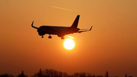 A plane flying into the sunset.