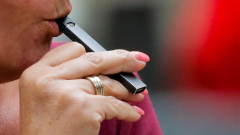 A woman vapes a JUUL