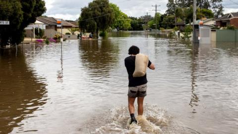 Man carries sandbag through flooded street