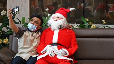 A man takes a selfie with Santa Claus, during a hand hygiene education event at Wockhardt hospital.