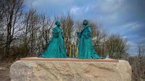 bronze sculpture of two women in Puritan dress