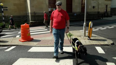 Nick Lancaster crossing a road with his guide dog