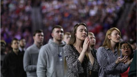 Students with hands pressed together in prayer