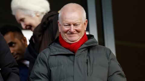 Bristol City owner Steve Lansdown wears a grey coat with a red scarf while stood in the director's box at Ashton Gate during the Championship game with Preston North End on 4 January 2026