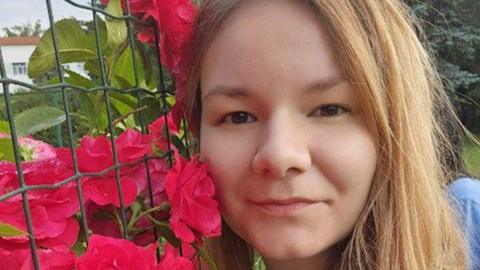 Kateryna Karabadzhak next to a fence with pink flowers