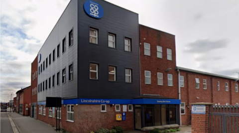 A large brick and grey-cladded office building, with 'Lincolnshire Co-op' written on a large blue sign on the front.
