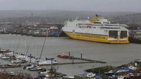 A yellow and white Transmanche ferry in a port.
