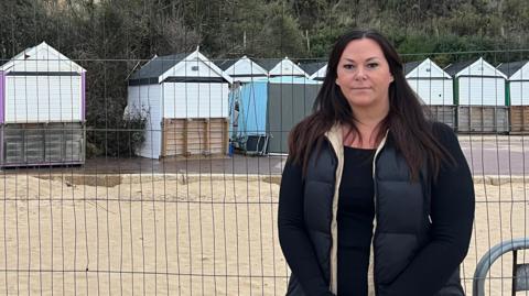 Natalie Carr stands in front of the cordoned-off beach huts