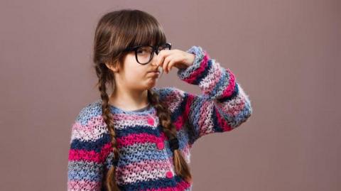 A girl holding her nose.