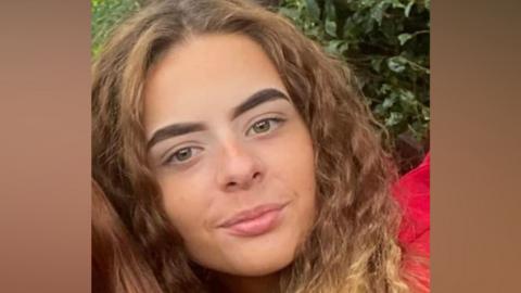 A close-up photograph shows Alisha Ponter with long hair looking towards the camera outdoors. The image focuses on her face and shoulders and is cropped from a larger photograph.