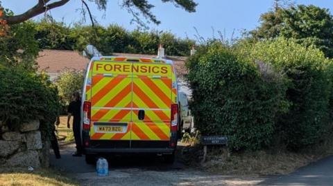A forensics van is pictured next to a hedge at Widdecombe's home