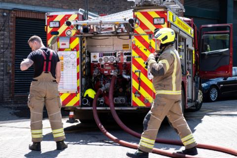 Fire engine and fire fighters attending a fire in a public car park.