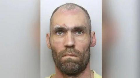 Mugshot of convicted sex offender Robert Emmerson. He has short, receding and greying hair and a beard.