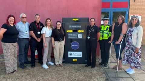 People stand either side of a new knife bin outside Doncaster Fire Station. Second from left to right: Damian Allen, CEO Doncaster Council; John Hodson, Doncaster Station Manager; Sally Jameson MP; Councillor Gemma Cobby; Clair Victory, SYFR; PC Hannah Cowling; Lisa Theobald; Kilvinder Vigurs, deputy mayor for policing and crime.
