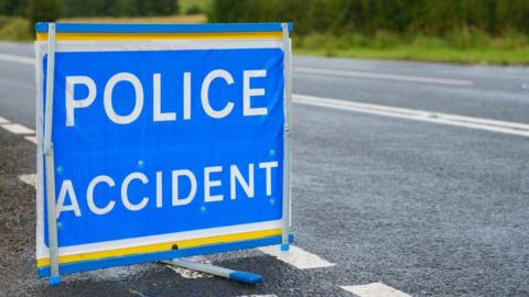 A police accident sign, bold white letters on a blue sign.
